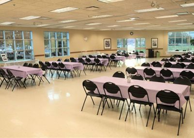 Room set up with multiple chairs and tables, covered with pink tablecloth