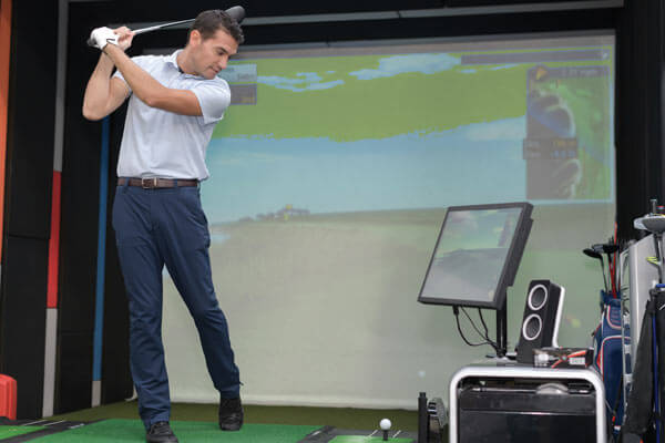 Man practicing golf swing using golf simulator