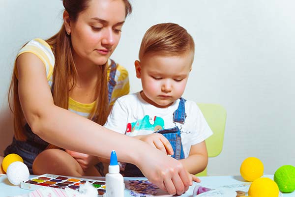 Mom helping a toddler with a craft project.