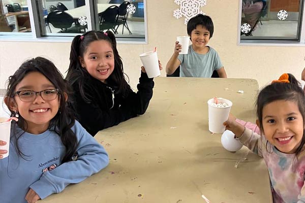 A group of kids sitting around a table, smiling and eating popcorn