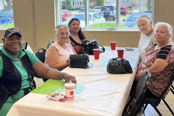 A group of seniors sitting by a table, playing bingo at Leoni Complex